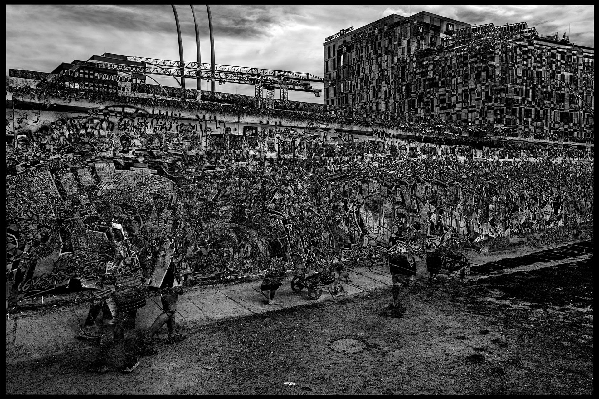 The second composition shows another section of the Berlin Wall, which is also painted. A group of people walks in front of the Wall, only the legs of the people and the lower part of a baby carriage are recognizable. Behind the wall, multi-storey residential or office buildings can be seen next to construction cranes. The textures of the facades and the wall are graphically and attractively distorted by the overlays.