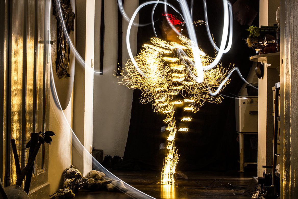Fotografische Licht-Inszenierung, Einstellung 7. Eine Frau erstrahlt durch Lichtspuren, die durch Langzeitbelichtung die Körperbewegungen nachzeichnen.