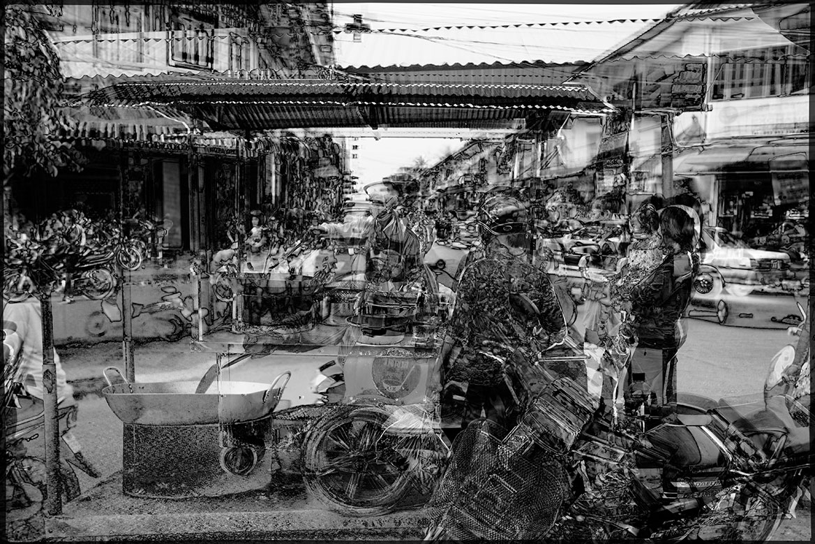 Kulisse in Phnom Penh mit einem Imbissverkäufer in einem typischen Straßenzug.