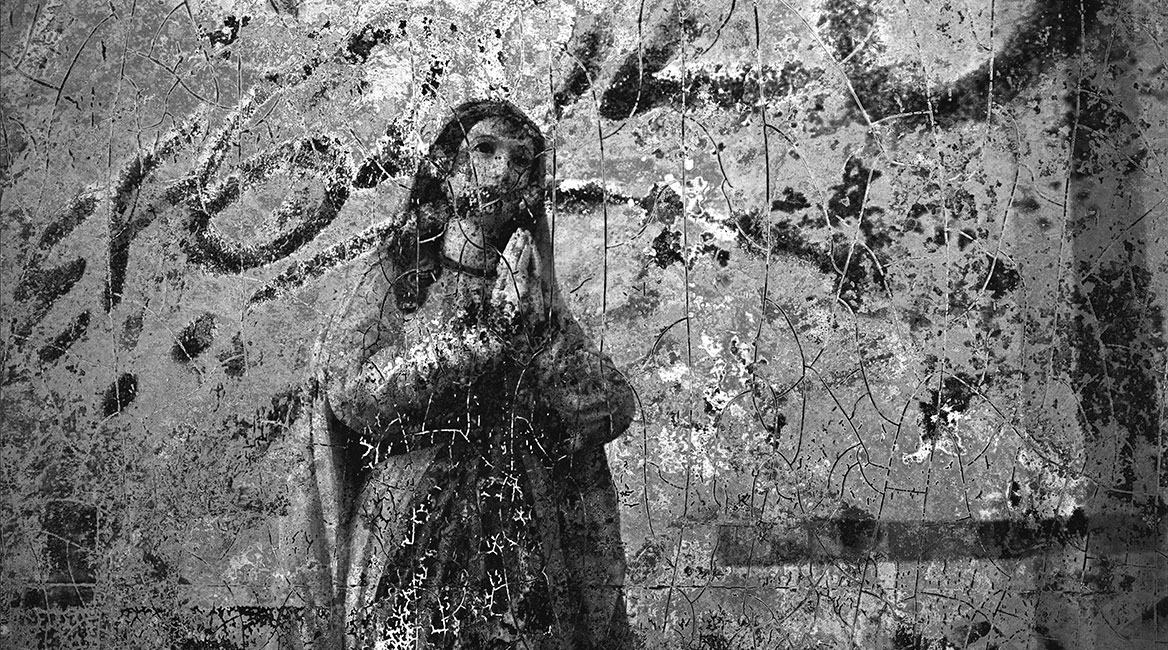 Das Marienbildnis mit der betenden Darstellung von Maria ist durch Risse und Graffitisprühungen gestört.