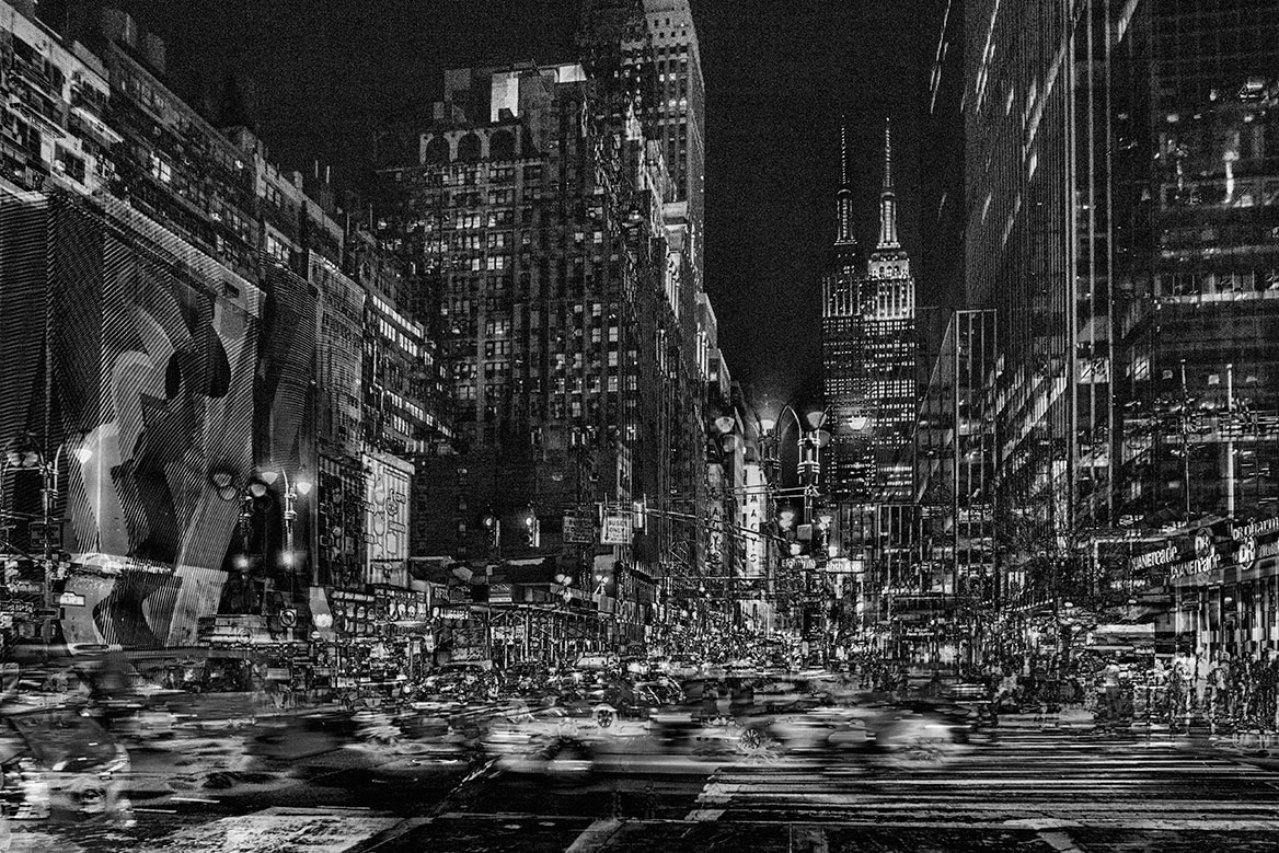 Das Empire State Building im Hintergrund. Im Vordergrund sieht man die verwischten Lichtspuren der Autos im Abendverkehr.