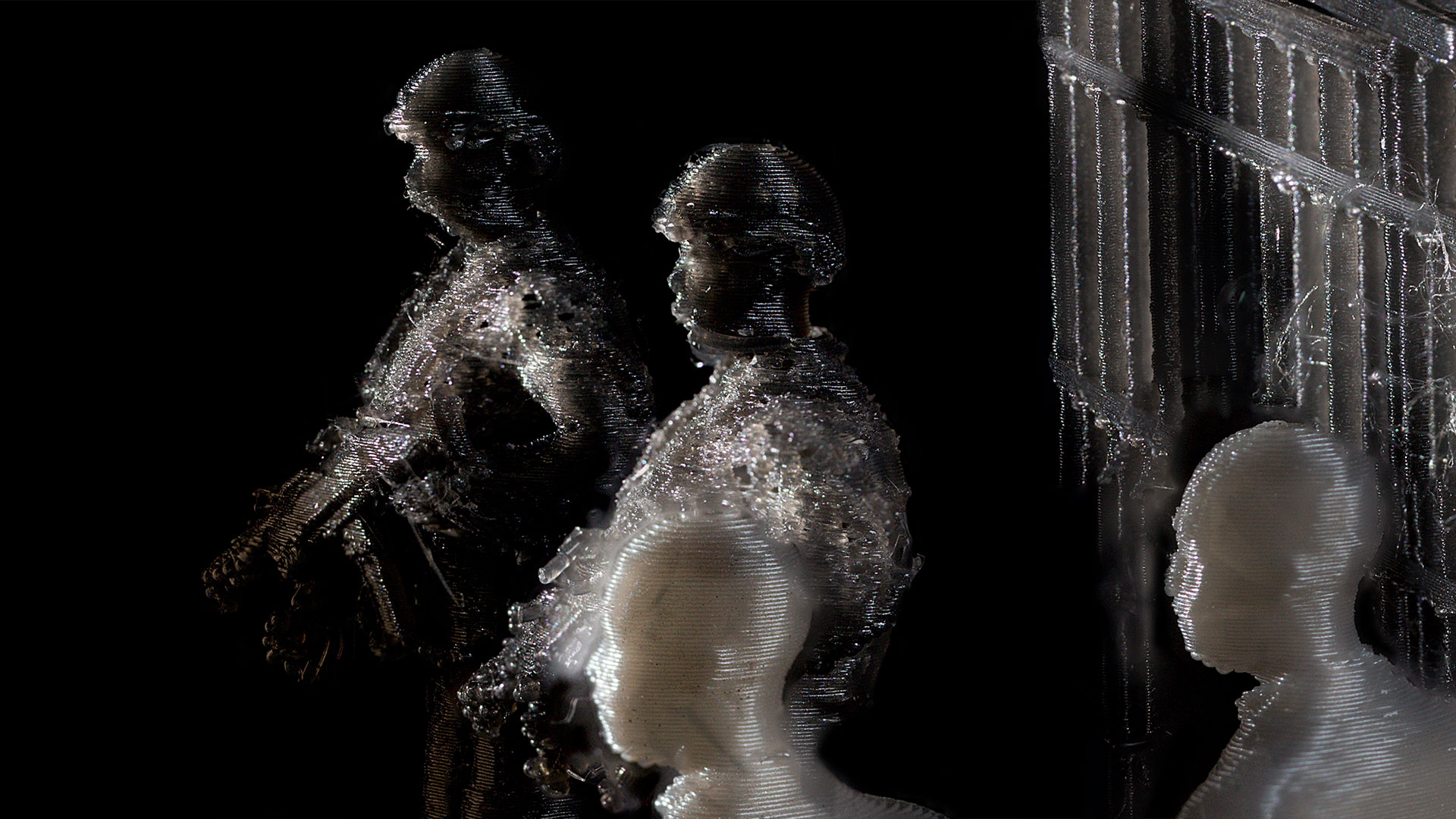 A prison cage, two guards, and two court witnesses stand against a black background. The detail shows the details of the 3D print output.